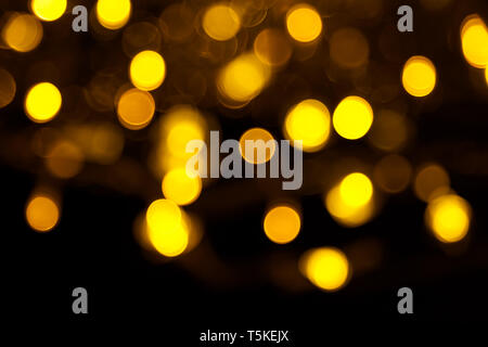 Abstrakte gold Bokeh auf schwarzem Hintergrund. Defokussierten gelb leuchten, abstrakte Textur. Stockfoto