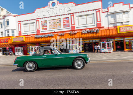 Der MG MGB Sportwagen fährt an der Sunspot-Spielhalle auf der Marine Parade vorbei, Southend on Sea, Essex, Großbritannien. Oldtimer am Strand Stockfoto