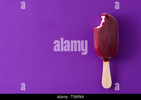 Gebissen Erdbeere popsicle auf Violett Hintergrund. Ansicht von oben. Copyspace Stockfoto