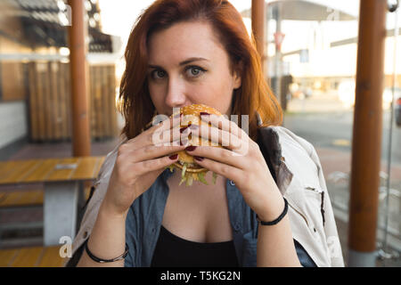 Hamburger close up - junge Frau Essen in Fast-Food-Restaurant - Cheeseburger, mittlere Pommes und Soda Stockfoto