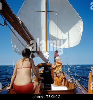 1970 s Segelboot. Eine Familie ist, genießen Sie einen Tag am Meer auf Ihren hölzernen Segelboot. Der Wind die Segel füllt. Die beiden Kinder tragen das Leben wests. Schweden 1970 s Stockfoto