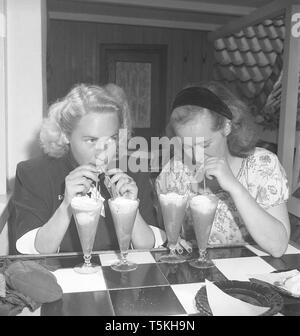 1940 Schauspielerin. Ein Glas des Dessert Getränke ist nicht genug. Diese beiden jungen Frauen haben je zwei Gläser und Getränke von Ihnen mit Strohhalmen. Foto Kristoffersson ref U 115-1. Schweden 1946 Stockfoto