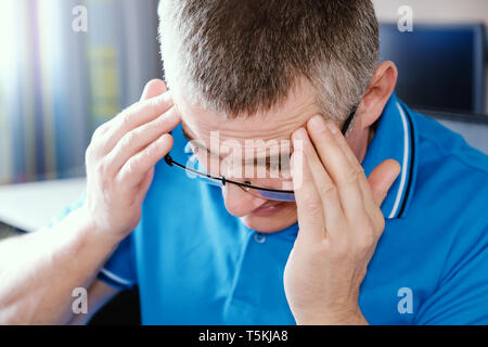 Der Mann mit der Brille leidet unter Depressionen. Probleme im persönlichen Leben und bei der Arbeit. Stress und Depressionen. Migräne ist eine Folge von Stress. Stockfoto