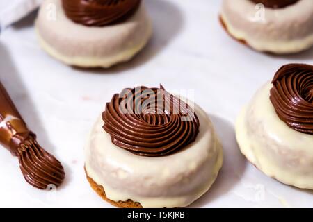 Triple Chocolate Donuts mit Cremigen Ganache sitzen auf weißem Marmor mit Paspel Tipp auf der Seite Stockfoto