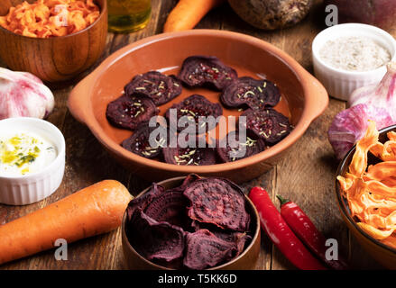 Cups mit Gemüse Chips und Ganzes Gemüse auf Holz- Hintergrund. Stockfoto