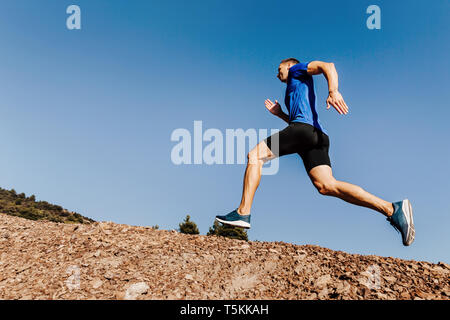 Athlet runner bergauf Trail auf blauen Himmel Hintergrund ausgeführt werden Stockfoto