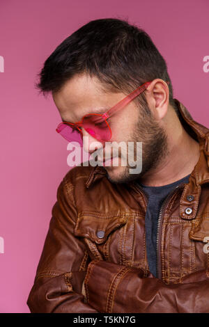 Foto von Brunet in rosa Brille und Lederjacke auf leere rosa Hintergrund Stockfoto