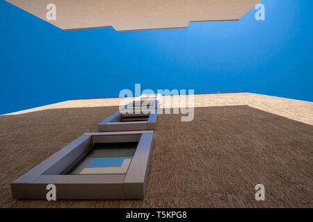 Interessante Architektur mit Windows in einer Linie nach oben und blauer Himmel in eine Schlucht von Häusern Stockfoto