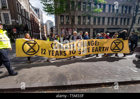 London, Großbritannien. 25. April 2019. Eine Gruppe von Aussterben Rebellion Demonstranten tragen ein Banner "Klimawandel - 12 Jahre zur Rettung der Erde" im März bis Holborn zurück zu Marble Arch nach der Anwendung von Maßnahmen in der Londoner City. Als sie marschierten sie sangen und sangen ihre Forderungen für die Regierung ein Klima Notfall, Für Null CO2-Emissionen bis 2025 und eines Bürgers. Dieser erwartete war der letzte Tag des Lagers bei Marble Arch zu erklären. Peter Marshall / alamy Leben Nachrichten Stockfoto