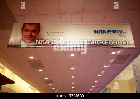 Ein Foto von NRA-ILA Executive Director Chris W. Cox ist auf einem Banner über einen Flur mit dem Indiana Convention Center. Anbieter bereiten sie Ständen in der Halle vor der National Rifle Association (NRA) Übereinkommen auf dem Indiana Convention Center in Downtown Indianapolis. Stockfoto