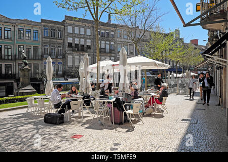 Essen und trinken die Menschen sitzen an Tischen im Freien auf einer Terrasse Pflaster Restaurant mit Sonnenschirmen im Frühjahr sunshine Porto Portugal KATHY DEWITT Stockfoto