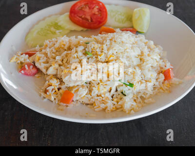 Gericht der asiatischen Küche - gebratener Reis mit Ei, Huhn Fleisch und Gemüse auf einem Schild auf dem Holz Tisch in einem thailändischen Restaurant Stockfoto