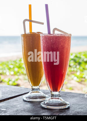 Zwei Gläser mit kalten Getränken auf dem Tisch im Restaurant. Mango und Wassermelone Smoothie in Glas Tassen in ein thailändisches Restaurant mit Blick auf das Meer Stockfoto