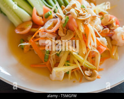 Authentische traditionelle Salat mit Papaya, frisches Gemüse und Kräuter, Fisch und Meeresfrüchte auf weiße Platte in Thai Restaurant Stockfoto