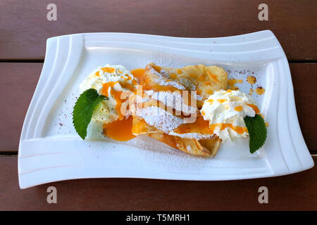 Palatschinken (Pfannkuchen) mit Aprikosenmarmelade und Eis, ein traditionelles österreichisches Dessert. Stockfoto