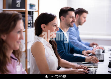 Lächelnden jungen Geschäft Leute sitzen in einem EDV-Zeile Stockfoto