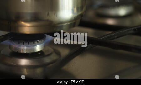 Ein Mann oder eine Frau, der eine Feuer auf eine automatische elektrische Zündung auf einem Gasherd und setzt auf eine Metallwanne. slow motion Close up in 4K. Stockfoto