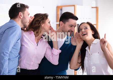 Business Kollege Whispering geheimen Klatsch zu Staunenden Frau mit weit geöffneten Mund geschockt Stockfoto