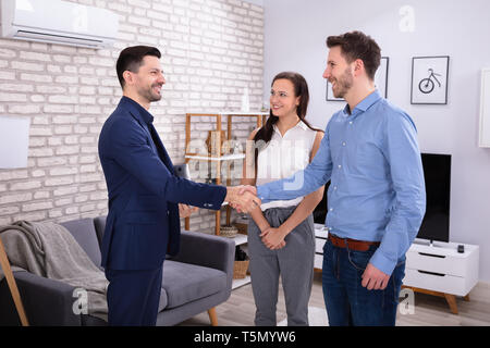 Lächelnd männlichen Immobilienmakler Händeschütteln mit seinen Kunden in der neuen Heimat Stockfoto