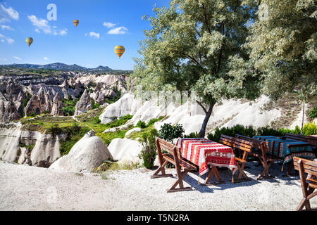 Restaurant in Göreme mit Blick auf Tuffstein Formationen und Heißluftballon in Kappadokien, Türkei Stockfoto