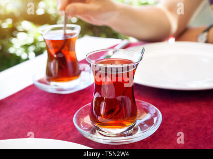 Türkischer Tee im Restaurant im traditionellen Glas auf dem roten Tisch in der Türkei Stockfoto