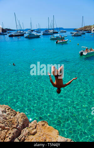 Junge Jungen ins Meer springen. Cala Salada Strand. Santa Agnés de Corona. Ibiza. Balearen. Spanien. Stockfoto