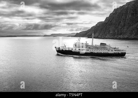 Moody Schwarz-weiß-Foto des historischen Hurtigruten-Schiffs MS Lofoten, Sailing Northbound, weit über dem norwegischen Polarkreis, Norwegen. Stockfoto