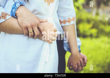 Mann umarmt Frau und die Hand in der ukrainischen traditionelle Kleidung. Bestickte Kleidung von blauen und gelben Farben. Stockfoto