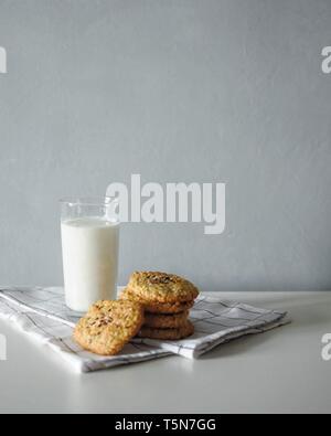 Glas Milch mit homemeade Ingwer oatmeal Cookies mit weißen Handtuch auf grauem Hintergrund Stockfoto