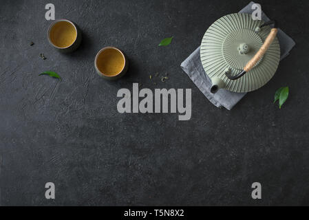 Teekanne und Teetassen auf schwarzem Hintergrund, kopieren. Traditionelle asiatische Tee Set Teekanne und Teetassen Keramik mit grüner Tee und Kaffee verlässt. Stockfoto