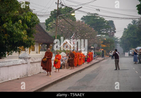 Luang Prabang, Laos - März 24, 2019: Touristen mit Essen bietet der buddhistischen Mönche in den frühen Morgen. Stockfoto