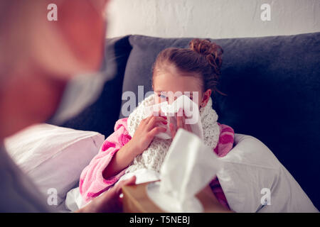 Kleine Dunkelhaarige mit Serviette, während mit laufender Nase Stockfoto