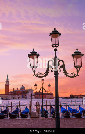 Traditionelle italienische Gondeln zu den Polen in Europa Venedig, in der Nähe der Innenstadt und Saint Mark Square mit einem Hintergrund Blick auf die Kirche von S günstig Stockfoto