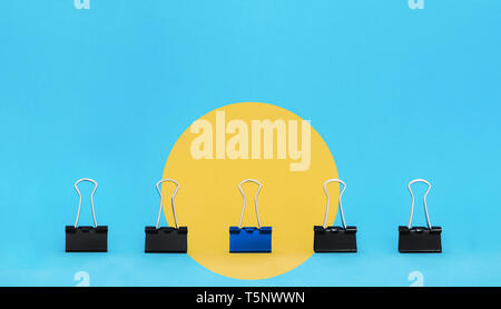 Einzigartige, Führung, Individualität und anderes Konzept denken. Bürobedarf, blau binder Büroklammer heben Sie sich von anderen Clips in gelber Kreis Stockfoto