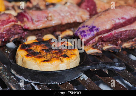 Köstlichen argentinischen Provolone Garn Käse (Provoleta), die in einer gusseisernen Pfanne über der Grill der Grill gekocht wird, Buenos Aires, Argentinien Stockfoto