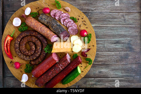 Große mit Würstchen. Viele Arten von Wurst, geräucherter Käse, frisches Gemüse auf einer hölzernen Fach Produkte in den Urlaub. Die Ansicht von oben Stockfoto