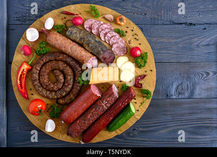 Große mit Würstchen. Viele Arten von Wurst, geräucherter Käse, frisches Gemüse auf einer hölzernen Fach Produkte in den Urlaub. Die Ansicht von oben Stockfoto