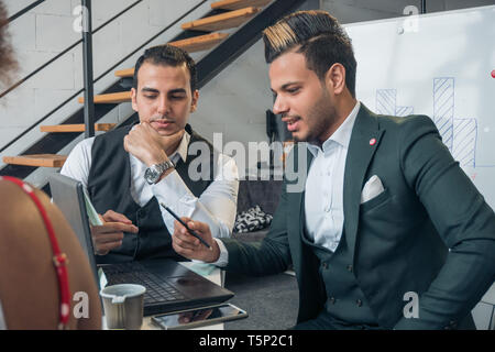 Die unterschiedlichen nationalen Jugendlichen bereite einen Business Präsentation und Blick auf den Laptop. Das Konzept der Sitzung im Büro Stockfoto