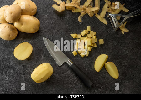 Messer schneiden Kartoffeln von texturiertem schwarzen Hintergrund. Foto von oben Stockfoto
