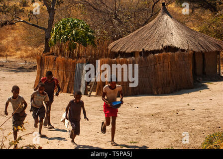 Jungen und Mädchen vor ihren traditionellen Gras Hütte läuft, Caprivi Strip, Namibia Stockfoto