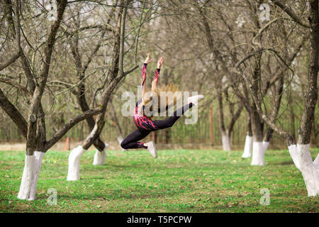 Rhythmische Gymnastik. Junge turnerin Mädchen im Park springen Stockfoto