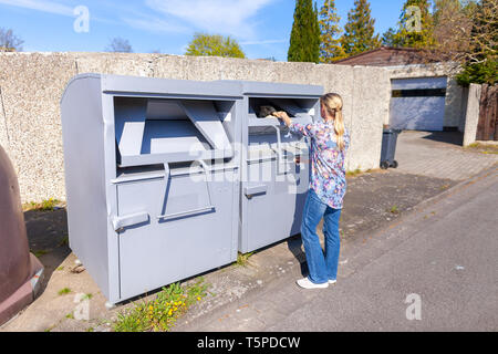 Junge Frau setzt eine Jacke in einem alten Kleidung Container Stockfoto