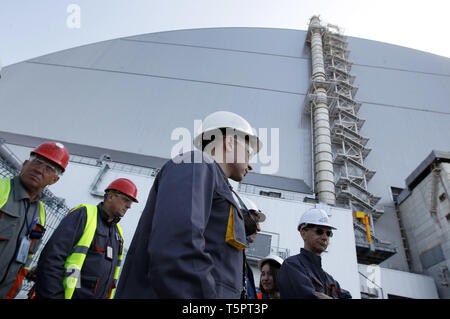 Kiew, Kiew, Ukraine. 26 Apr, 2019. Arbeitnehmer sind zu Fuß vor der neuen Schutzkonstruktion in der 4. Block des Kernkraftwerks Tschernobyl während des Jubiläums. Ukrainer markiert der 33. Jahrestag der Katastrophe von Tschernobyl. Die Explosion der vierte Block des Kernkraftwerks Tschernobyl am 26. April 1986 immer noch als der größte Unfall in der Geschichte der Atomenergie. Credit: Pavlo Gontschar/SOPA Images/ZUMA Draht/Alamy leben Nachrichten Stockfoto