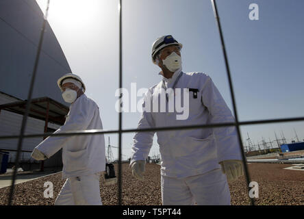 Kiew, Kiew, Ukraine. 26 Apr, 2019. Arbeitnehmer sind zu Fuß vor der neuen Schutzkonstruktion in der 4. Block des Kernkraftwerks Tschernobyl während des Jubiläums. Ukrainer markiert der 33. Jahrestag der Katastrophe von Tschernobyl. Die Explosion der vierte Block des Kernkraftwerks Tschernobyl am 26. April 1986 immer noch als der größte Unfall in der Geschichte der Atomenergie. Credit: Pavlo Gontschar/SOPA Images/ZUMA Draht/Alamy leben Nachrichten Stockfoto