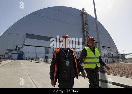 Kiew, Kiew, Ukraine. 26 Apr, 2019. Arbeitnehmer sind zu Fuß vor der neuen Schutzkonstruktion in der 4. Block des Kernkraftwerks Tschernobyl während des Jubiläums. Ukrainer markiert der 33. Jahrestag der Katastrophe von Tschernobyl. Die Explosion der vierte Block des Kernkraftwerks Tschernobyl am 26. April 1986 immer noch als der größte Unfall in der Geschichte der Atomenergie. Credit: Pavlo Gontschar/SOPA Images/ZUMA Draht/Alamy leben Nachrichten Stockfoto