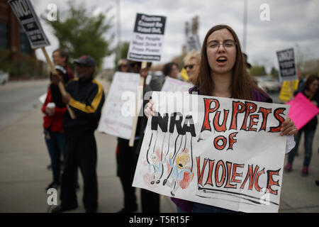 Indianapolis, Indiana, USA. 26 Apr, 2019. Eine Frau hält ein Schild mit der Aufschrift "NRB Marionetten von Gewalt.'' Als sie März zu Lucas Oil Stadium gegen die National Rifle Association und Präsidenten der Vereinigten Staaten Donald J. Trumpf, die festgelegt wurde, um eine Rede zu gun Unterstützer zu geben und der lobbyist Gruppe zu protestieren. Quelle: Jeremy Hogan/SOPA Images/ZUMA Draht/Alamy leben Nachrichten Stockfoto