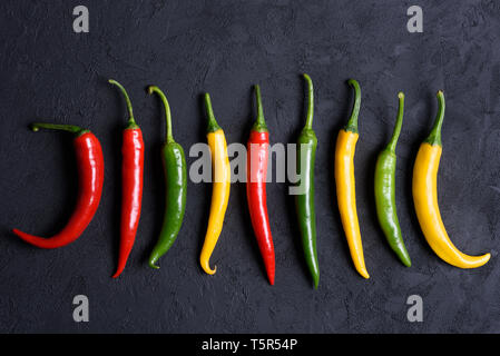 Verschiedenfarbige Peperoni auf dunklem Hintergrund Stockfoto
