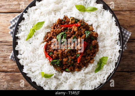 Pfannengerichte Basilikum Huhn mit Chili und Sojasauce mit Beilage von Reis close-up auf einem Teller auf den Tisch. horizontal oben Ansicht von oben Stockfoto