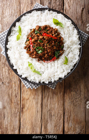 Thai basil Huhn mit pikanter Chili Pfeffer und Sojasauce mit garnieren Reis close-up auf einem Teller auf den Tisch. Vertikal oben Ansicht von oben Stockfoto