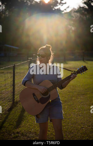 Junge Frau mit Gitarre in einem Feld Stockfoto